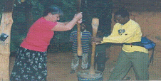 A guest pounding maize during a stay with a local family