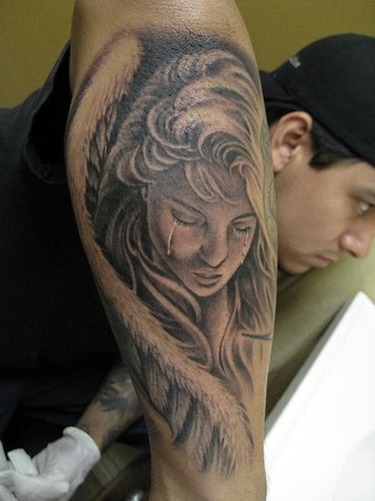 Crying angel tattoo on forearm.