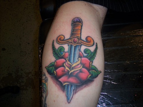 Rose and dagger on forearm tattoo.
