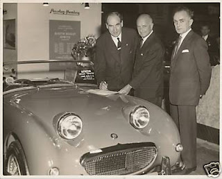 DONALD HEALEY, A G B OWEN & CHRIS SHORROCK SIGNING THE SHORROCK/HEALEY DISTRIBUTORSHIP AGREEMENT, MOTOR SHOW, EARLS COURT 1960