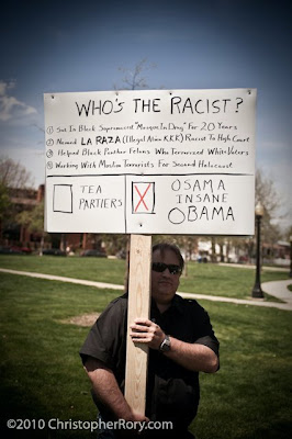 Beefy man holding big sign with lots of words making claims about Obama's support for terrorists