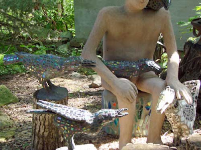 Seated figure surrounded by crows. He's petting one crow, another is on his lap.