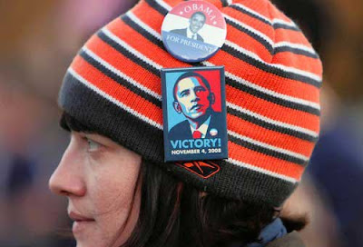 Young woman in striped red and blue knit hat with Obama buttons on it