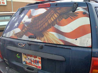 Back window of a Jeep Cherokee covered with an American flag and a bald eagle, plus eagle and flag license plate