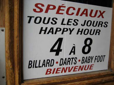 Happy hour sign at a bar listing Billiards, Darts and Baby Foot