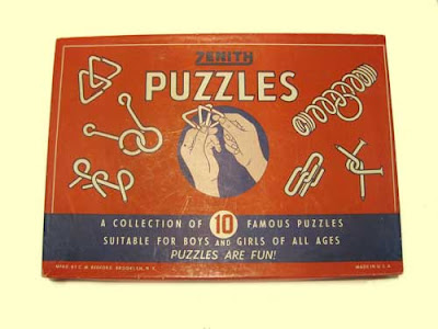 Red cardboard Zenith Puzzles box with illustrations of hands and metal puzzles