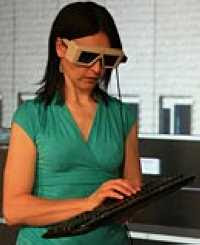 Wendy Powell wearing virtual reality goggles while using her keyboard to adjust graphics (2008)