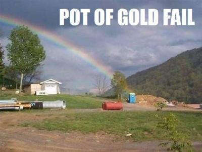 photo of a rainbow ending at an outhouse