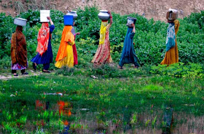 Pakistani women make their way towards their homes after collecting fresh water from a water point on the outskirts of Islamabad, Pakistan