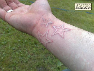 Três estrelas tatuadas com tinta branca no pulso