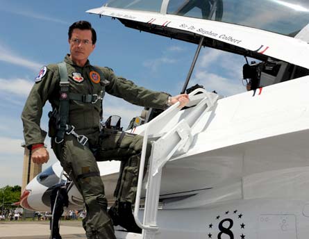 Above Colbert in a jumpsuit loading a sound bending jet craft named in his
