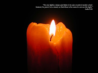 Candle glowing reddish yellow with black background with Luke8_16 verse photo