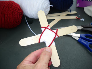 Wood stick cross being weaved around with yarn
