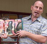 A color photo of Jon Scieszka reading poetry from his book ‘Science Verse’ at a book signing.