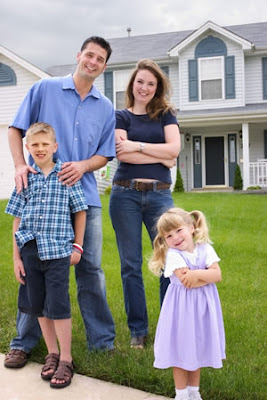 a very happy family standing in front of big house