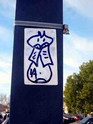 a graffiti cat on a sticker on a light pole in La Canada California