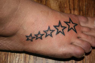 Tattoo com 5 estrelas de tamanhos diferentes e na ordem crescente,desenhadas no peito do pé