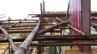 Bamboo scaffolding around a small building in Hong Kong from directly beside the bottom supports. Image of bamboo scaffolding around a small building in Hong Kong from directly beside the bottom supports.