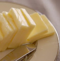 Pats of butter on a plate, and the blade of a butter knife.
