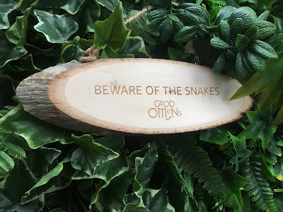 photo of a wooden sign against green foliage, reading 'beware of the snakes'