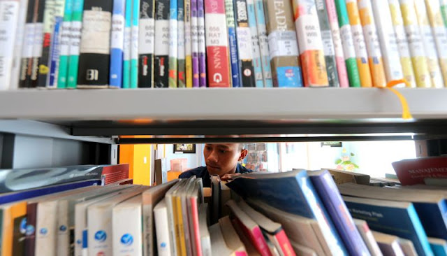 Sedang mencari buku di perpustakaan