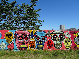 Graffiti on wall running up to site of bridge - spray painted, colourful skulls of the type seen at Day of the Dead.  Photo by Kevin Nosferatu for the Skulferatu Project