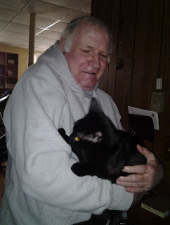 Tod Eaton holding a black cat with some angst in his face.