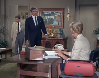 Columbo and Dr. Fleming enter his office. Columbo is wearing the famous raincoat.