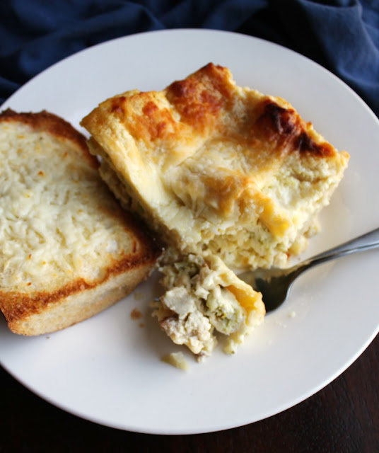 Creamy layers of chicken broccoli alfredo goodness in lasagna form. This is sure to become a favorite dinner! first bite of chicken broccoli alfredo on fork with piece of cheesy garlic bread on plate
