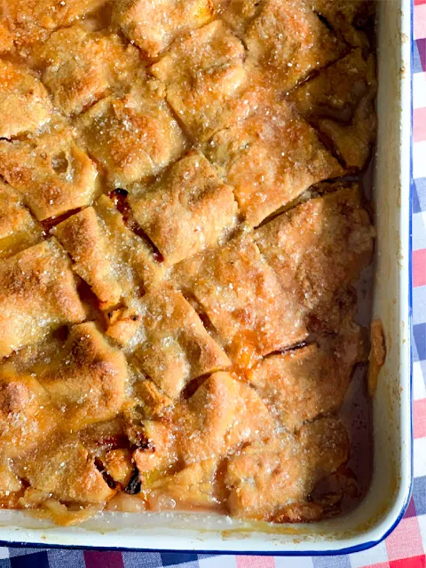 Peach Dumpling Cobbler, a cobbler made with fresh sliced peaches layered between three layers of sweet, tender, buttery dough.  Boiling water is poured over the whole cobbler, where all the magic happens.  The dough transforms, making sheets of dumplings.