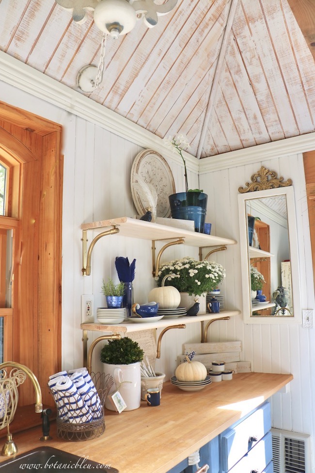 Midnight blue dishes with gold rims coordinate with open shelves supported by gold brackets