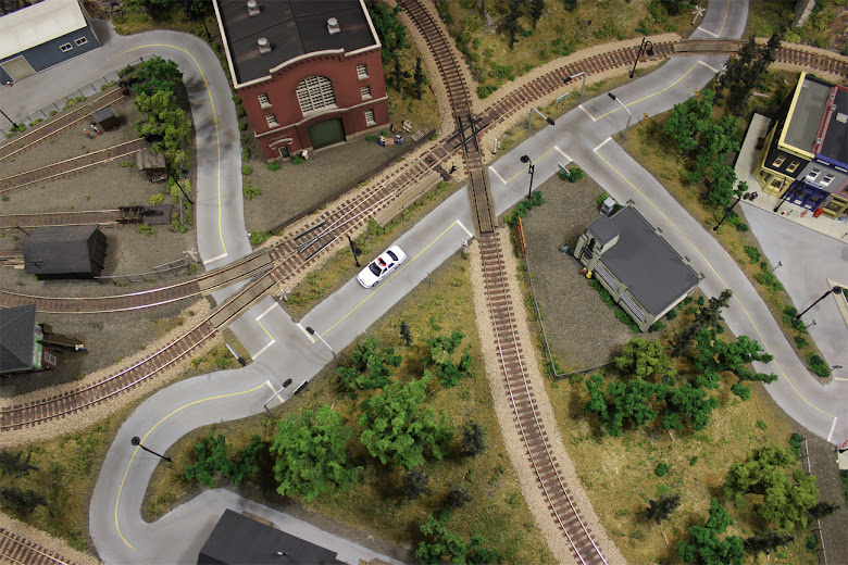 An areal view of roads, tracks, grade crossings, a turnouts, buildings and forest scenery