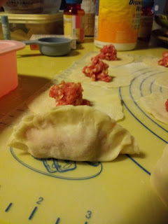 rounds of dough with filling in the middle. One round is sealed with pleated edges upright