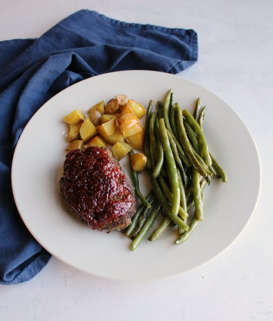 Make your whole homestyle meal on one sheet pan. Everyone can enjoy their own mini meatloaf along with roasted green beans and potatoes and there's only one pan to clean! dinner plate filled with a mini meatloaf, potatoes and green beans