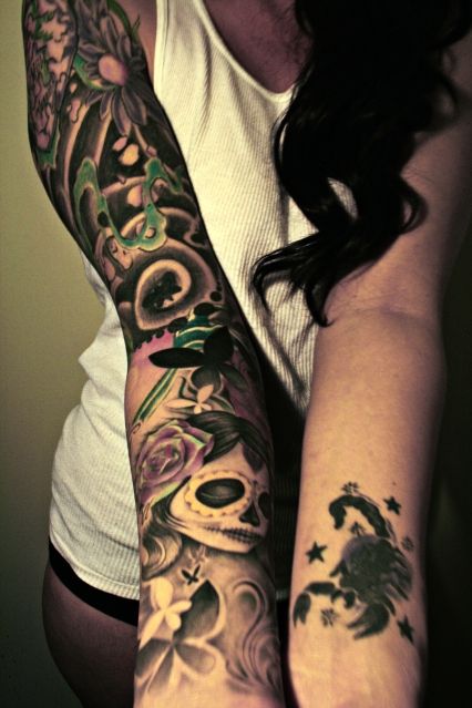 Chica posando con tatuajes de catrinas por el brazo