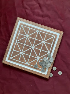A wooden board, with the geometric design of an Alquerque board painted on it