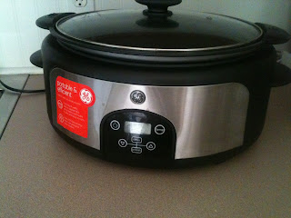 A crockpot sitting on a counter as a meal is cooked.