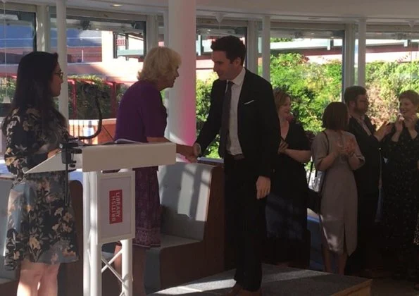 Camilla, the Duchess of Cornwall attended a literacy event for The Royal Society of Literature at the British Library. purple top and print skirt