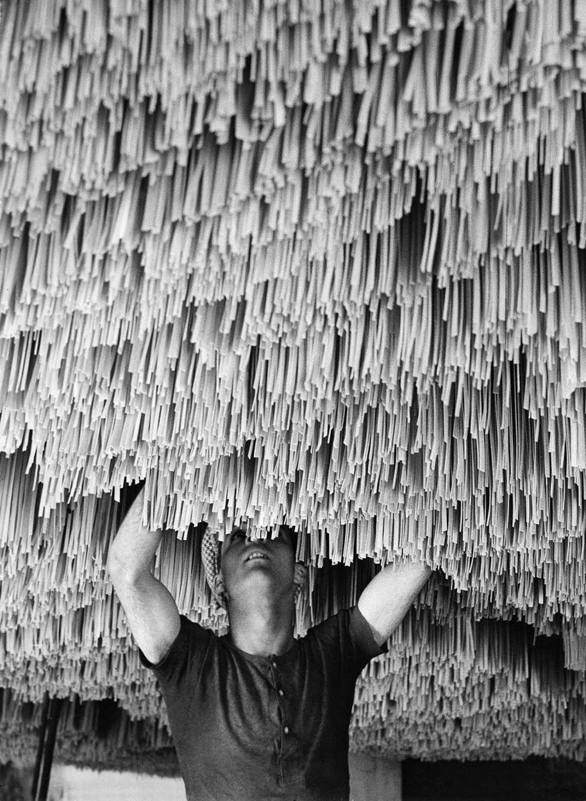 A worker hangs pasta to dry in a factory in Italy. 1932.