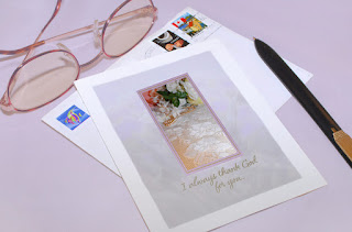 A note card with stamped envelope, pen and a pair of glasses.