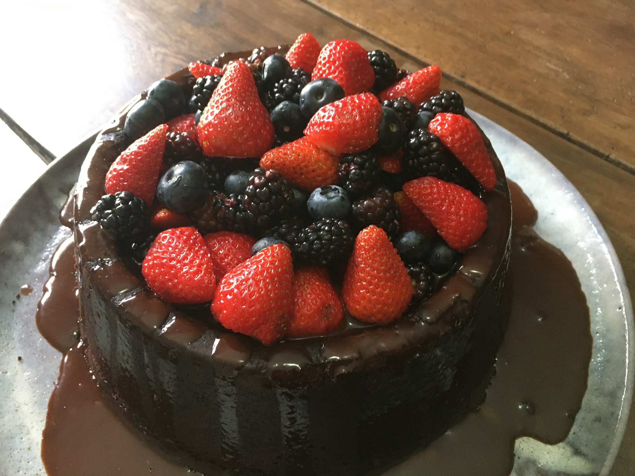 Bolo de aniversário coberto com frutas vermelhas e gotas de chocolate na  toalha de mesa branca conceito moderno de padaria