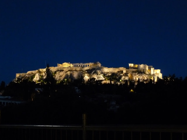 A view of the ruins of Acropolis lit up against a dark blue sky