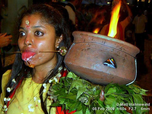 Street portrait of an agitated Malaysian Indian woman with pierced tongue and cheeks carrying a ceremonial offering during the 2009 Thaipusam Festival at Batu Caves. Thaipusam Festival, Malaysia, Kuala Lumpur, Batu Caves, kavadi attam, ceremonial sacrifice, ceremonial offering, Tamil woman, Hindu woman, Malaysian Indian woman, street portrait, ritualised piercing, ritualised mutilation, self-mutilation