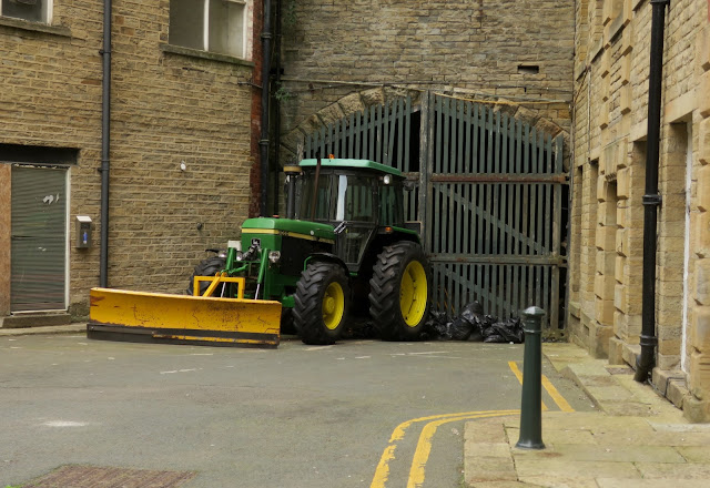 Green and yellow tractor in front of tall wooden gates.