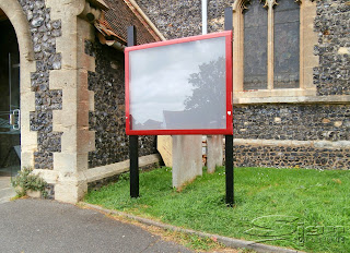 Lockable outdoor notice board freestanding mounted on a two metal poles.
