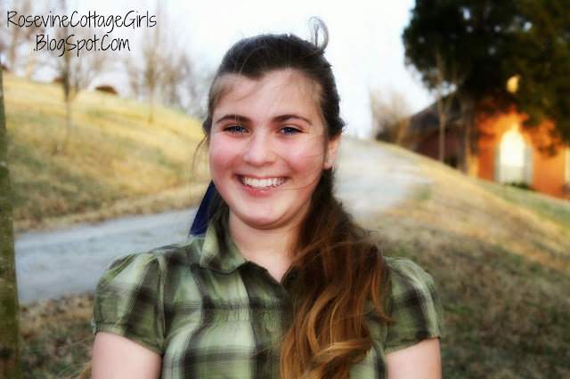 Young girl smiling on a country gravel road. She has long brown hair thrown over her shoulder and a green and white plaid top on. The article is about cherishing the sweet moments in life.