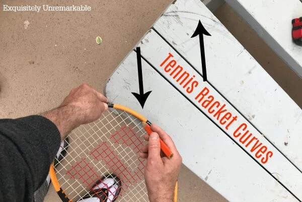 Using a tennis racket to draw a curve on wood with text that says tennis racket curves