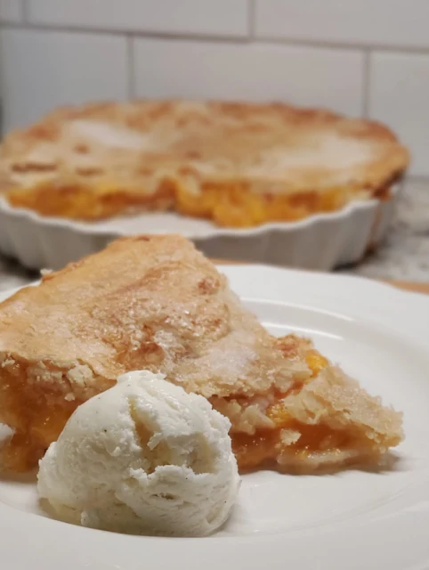 slice of peach pie with scoop of ice cream