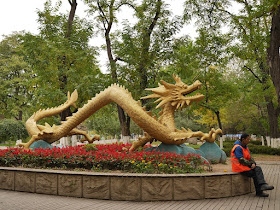 Man sitting with a large sculpture of a Chinese dragon immediately behind him