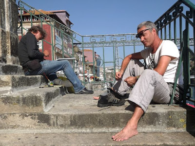 Dois homens sentados em escada na Ribeira do Porto com a Ponte Luix I ao fundo